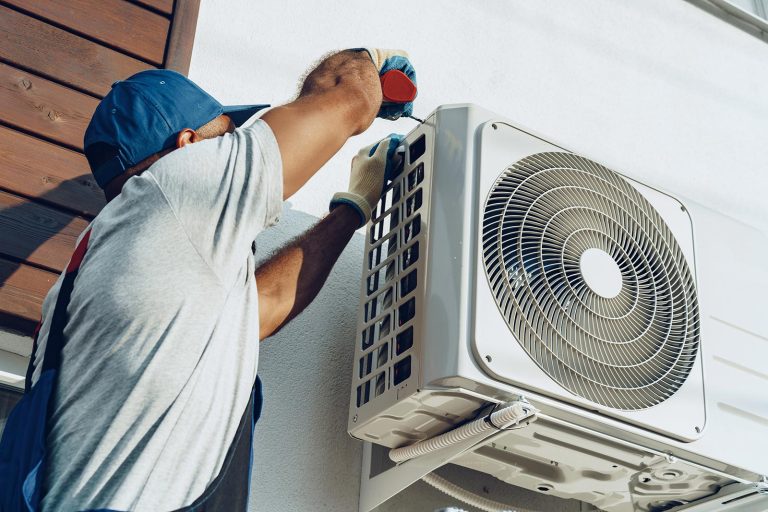 Repairman in uniform installing the outside unit of air conditioner close up